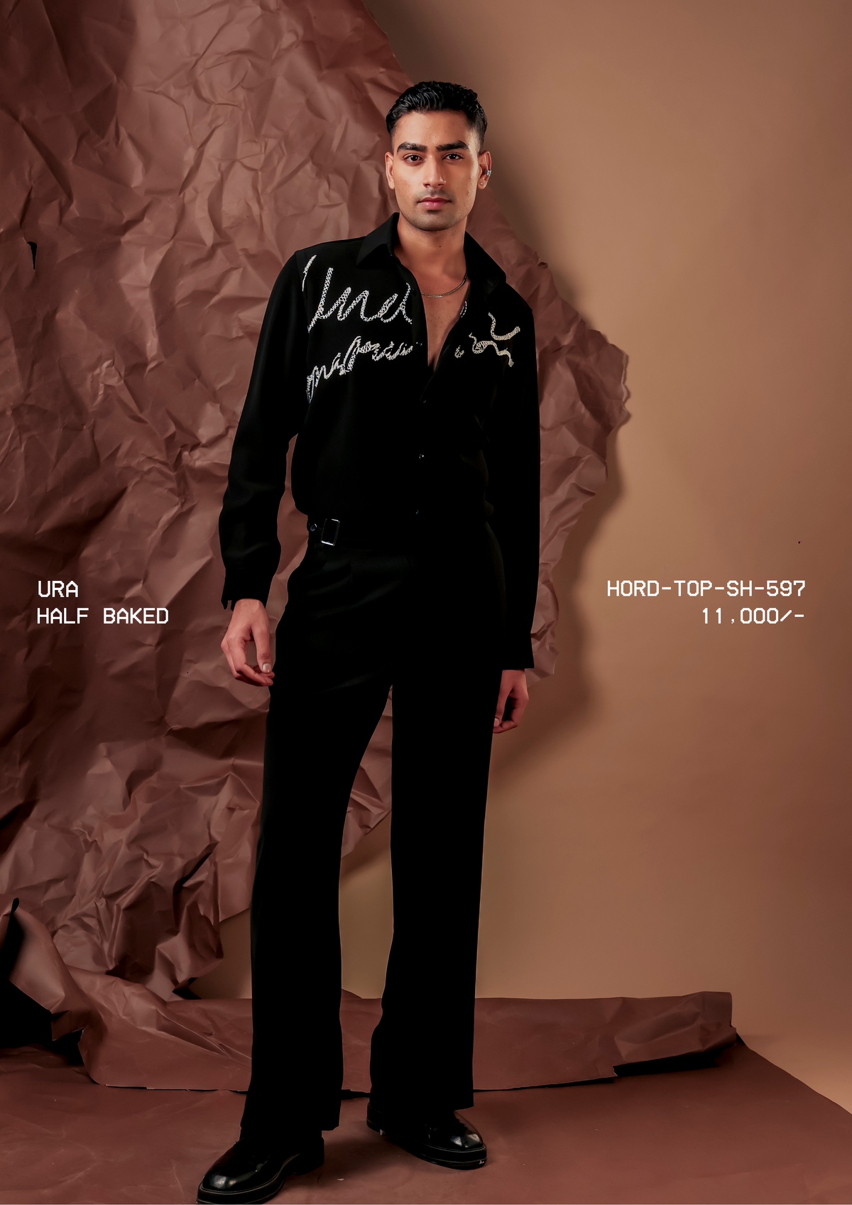 Man wearing HORD Half Baked black shirt with silver beaded cursive script, full-length studio shot