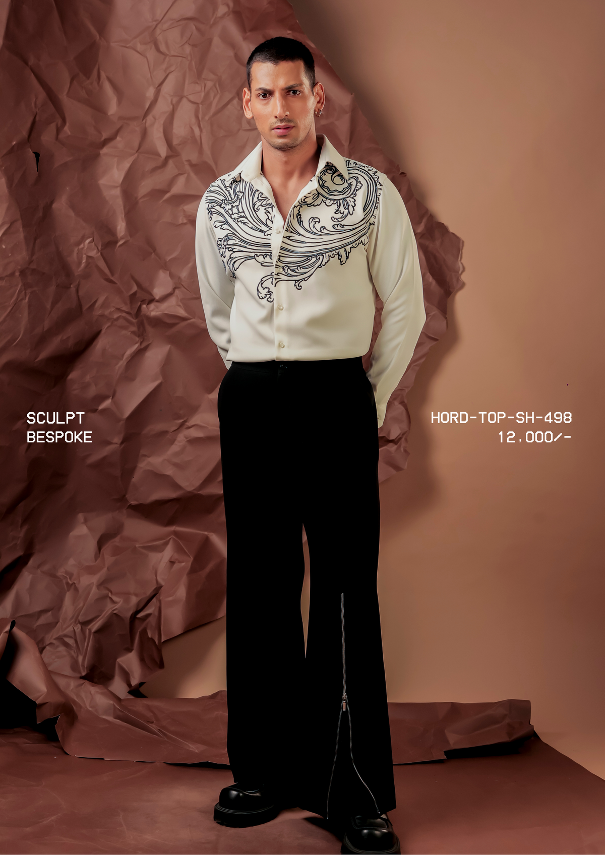 Man wearing HORD Bespoke ivory shirt with black baroque scroll embroidery across the shoulders, full-length studio shot