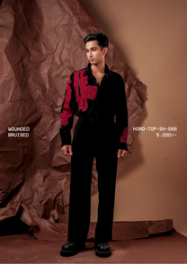 Man wearing HORD Bruised black shirt with raised crimson embroidery across chest and sleeve, full-length studio shot