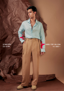 Man wearing HORD Co-Star pale aqua shirt with hot pink star appliques on the sleeves, styled with tan trousers