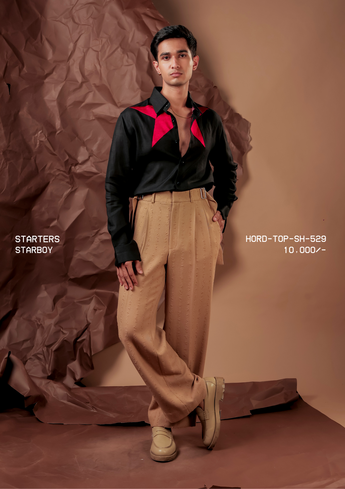 Man wearing HORD Starboy black shirt with hot pink star applique across the shoulders, styled with tan trousers