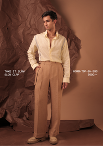Man wearing HORD Slow Clap pale lemon shirt with black and white cord-knot embroidery, styled with tan trousers