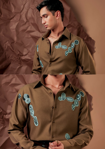 Close-up of HORD Somehow shirt showing aqua and black embroidered motifs on olive brown