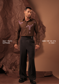 Man wearing HORD Suppouse chocolate brown shirt with pink beaded embroidery motifs, full-length studio shot