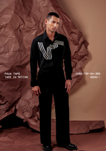 Man wearing HORD Tape In Motion black shirt with looping ivory striped tape motif, full-length studio shot