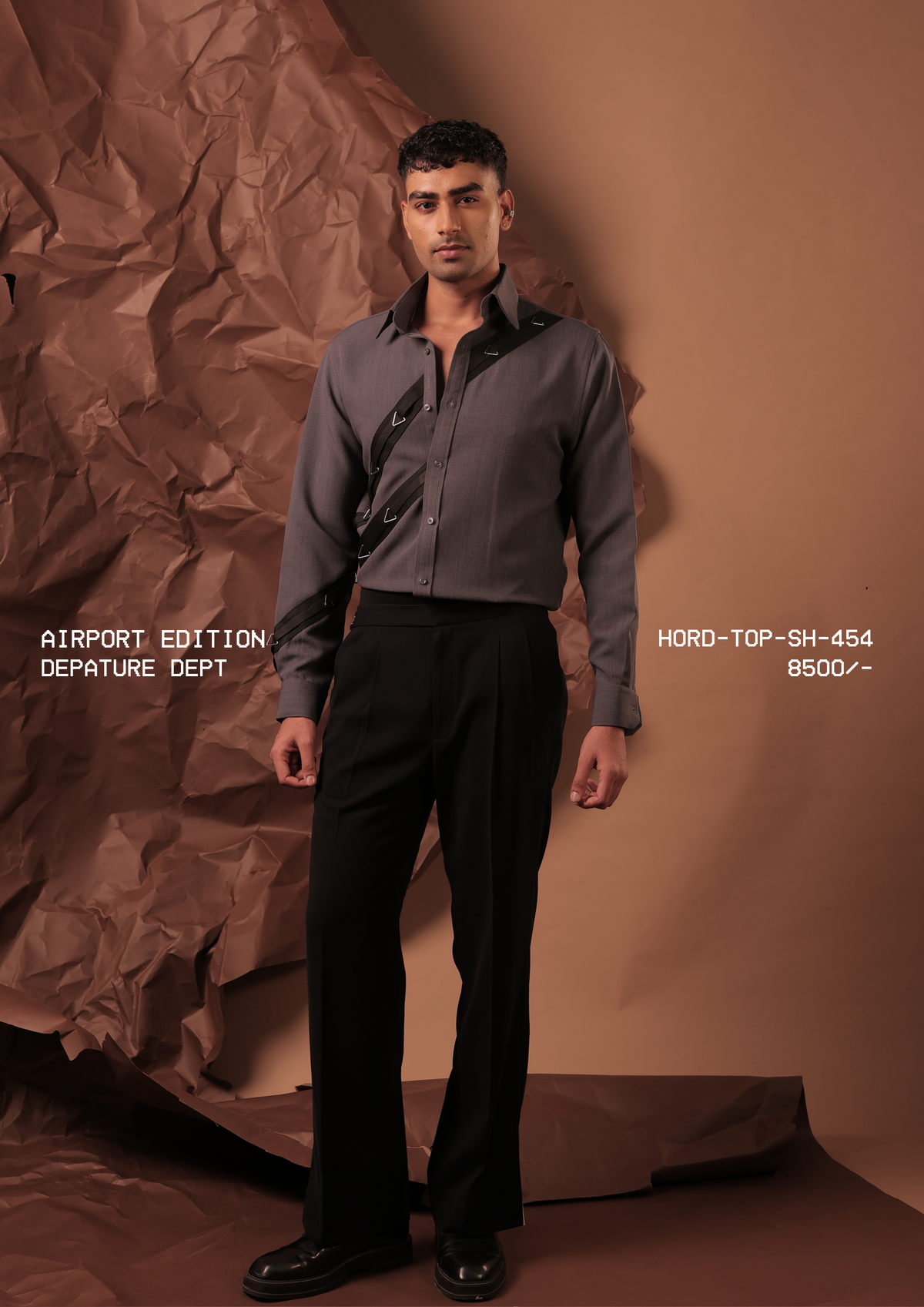 Man wearing HORD Depature Dept slate grey shirt with black diagonal straps and metal triangle hardware, full-length studio shot