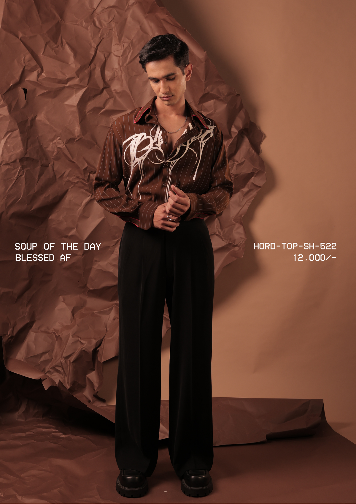 Man wearing HORD Blessed AF brown pinstripe shirt with ivory drip graffiti embroidery, full-length studio shot