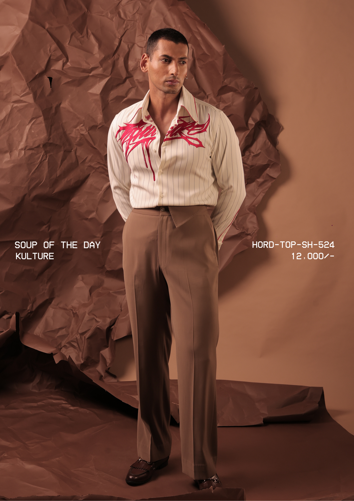Man wearing HORD Kulture ivory pinstripe shirt with fuchsia graffiti embroidery, styled with taupe trousers