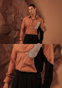 Detail of HORD Office of Misalignment shirt showing off-centre grid patch and curved black panel on terracotta