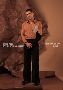 Man wearing HORD Office of Misalignment rust shirt with black side panel and grid-check chest patch, full-length studio shot