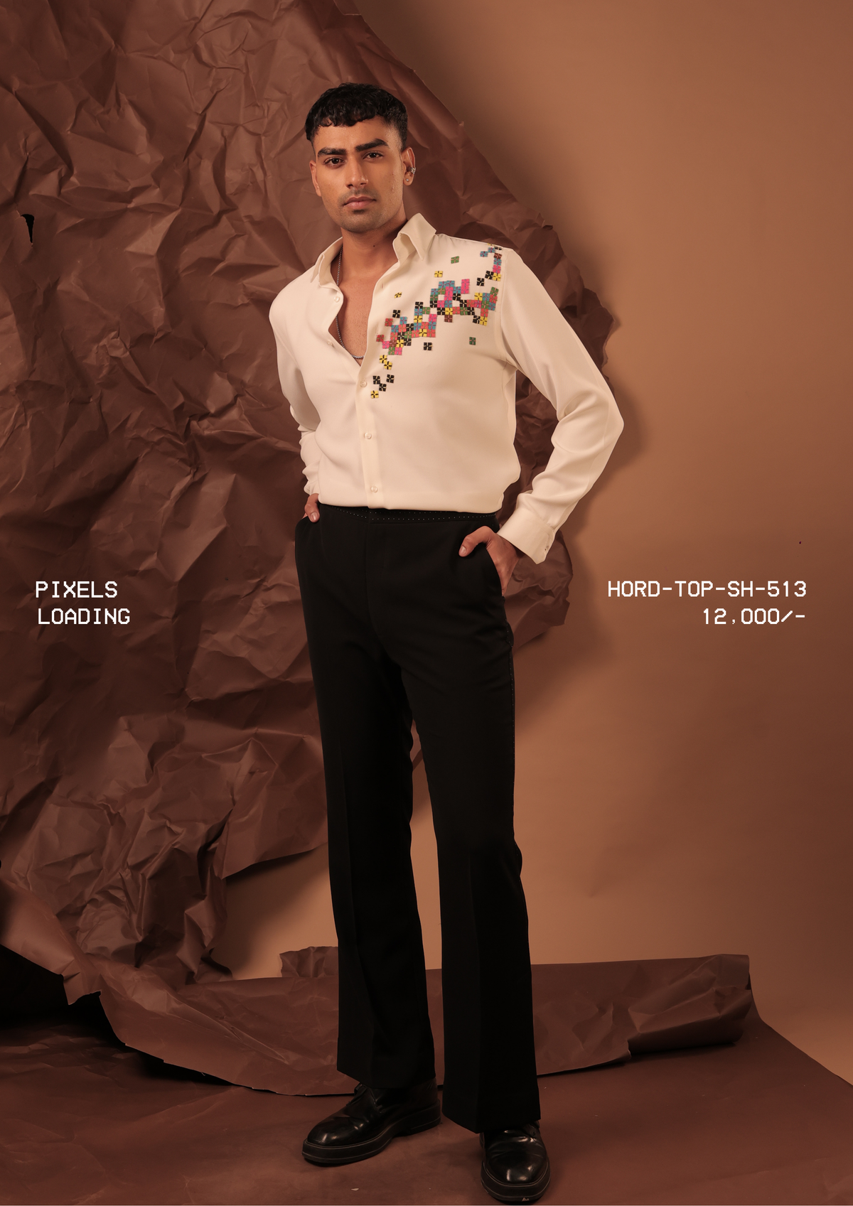 Man wearing HORD Loading ivory shirt with multicolour embroidered pixel squares, full-length studio shot