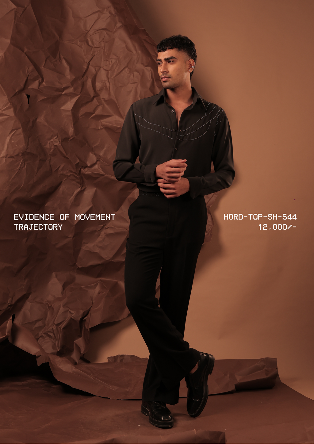 Man wearing HORD Trajectory black shirt with ivory topstitch arcs across the chest, full-length studio shot