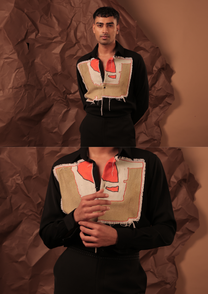 Close-up of HORD Beautifully Broken shirt showing frayed canvas panel painted in coral and ivory on black
