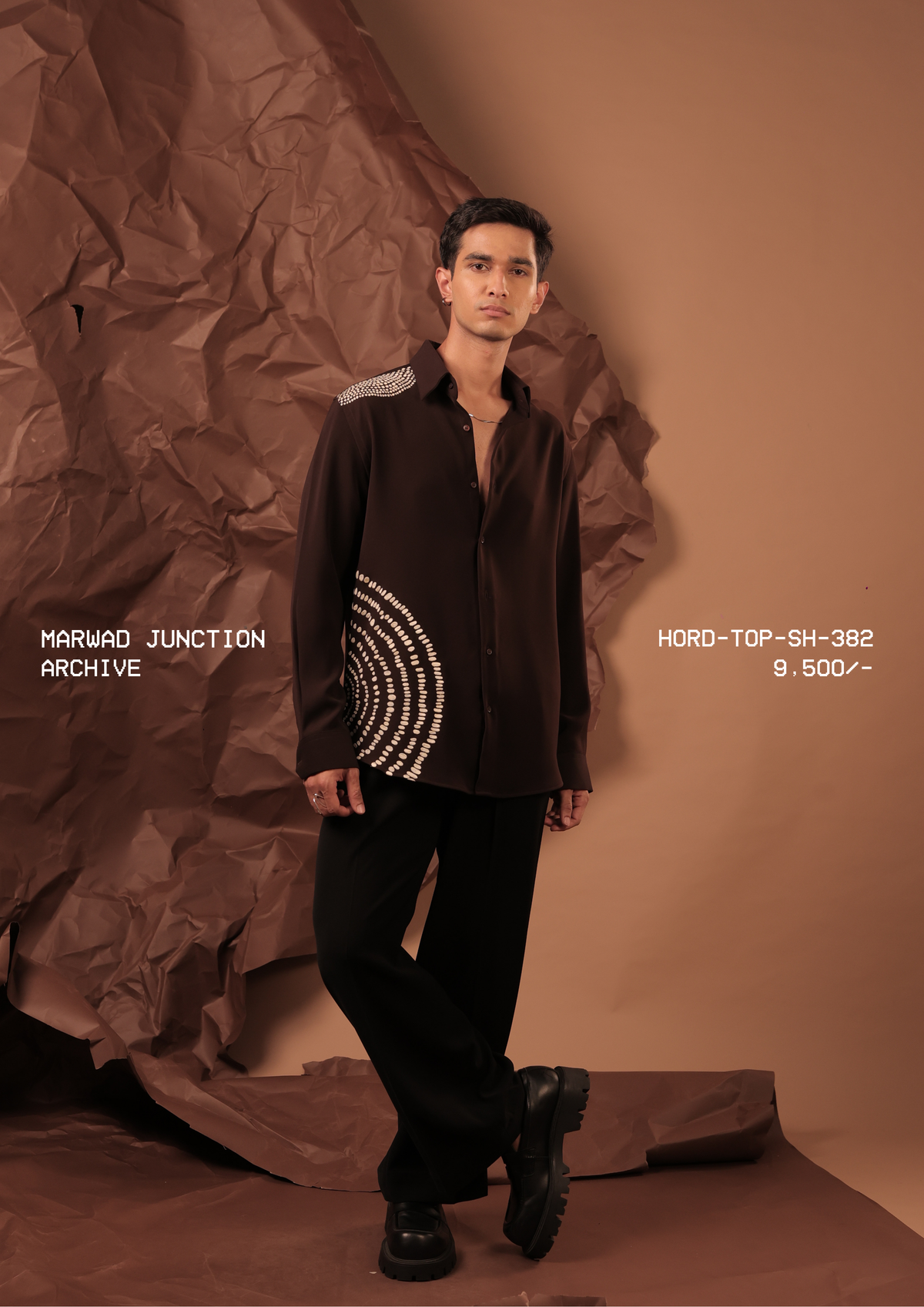 Man wearing HORD Archive dark chocolate shirt with concentric ivory dot embellishment at the hem, full-length studio shot